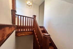 Stairs featuring vaulted ceiling and a chandelier