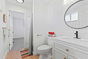 Bathroom with toilet, vanity, and wood-type flooring