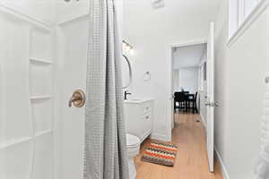Bathroom featuring toilet, vanity, a shower with shower curtain, and hardwood / wood-style flooring