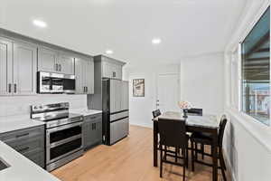 Kitchen featuring light stone countertops, stainless steel appliances, light hardwood / wood-style floors, and gray cabinets