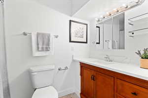 Bathroom featuring toilet, a shower with curtain, and vanity