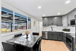 Kitchen featuring light stone countertops, a center island, stainless steel appliances, sink, and light wood-type flooring