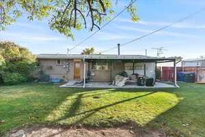Rear view of house with cooling unit, a patio area, and a yard