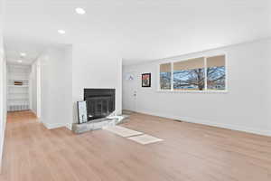 Unfurnished living room featuring light hardwood / wood-style floors and built in shelves