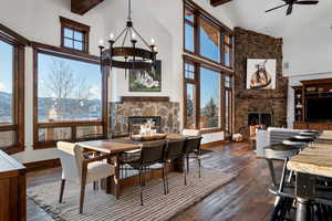 Dining area featuring dark hardwood / wood-style flooring, high vaulted ceiling, a stone fireplace, and beamed ceiling