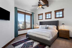 Bedroom with ceiling fan, lofted ceiling with beams, and carpet flooring