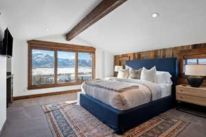 Carpeted bedroom featuring a mountain view, wood walls, and vaulted ceiling with beams