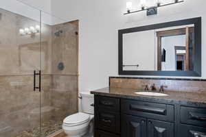 Bathroom with toilet, vanity, and a shower with shower door