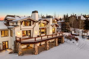 Snow covered rear of property with a deck