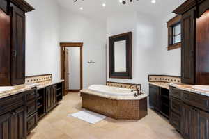 Bathroom with tile patterned flooring, tiled tub, and vanity