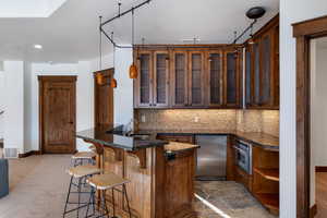 Kitchen featuring tasteful backsplash, kitchen peninsula, hanging light fixtures, a kitchen breakfast bar, and stainless steel appliances