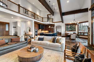 Living room with a notable chandelier, beamed ceiling, and a high ceiling