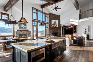 Kitchen with light stone counters, sink, stainless steel microwave, and a stone fireplace