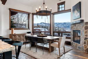 Dining area featuring a fireplace, a mountain view, hardwood / wood-style floors, and a notable chandelier