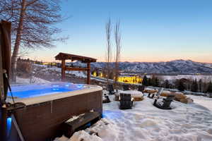 Snow covered patio with a mountain view and a hot tub