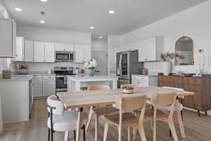 Kitchen featuring stainless steel appliances, white cabinetry, a kitchen island, and sink