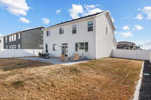 Rear view of house with a lawn and a patio
