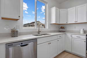 Kitchen featuring white cabinetry, light hardwood / wood-style floors, dishwasher, and sink