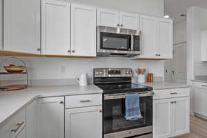 Kitchen featuring white cabinetry, appliances with stainless steel finishes, and light hardwood / wood-style floors