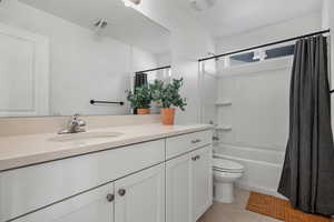Full bathroom with shower / tub combo with curtain, vanity, toilet, and tile patterned flooring