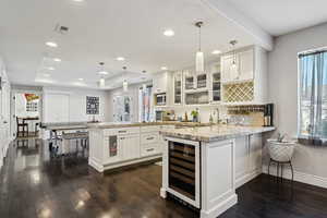 Kitchen featuring wine cooler, pendant lighting, kitchen peninsula, and white cabinets