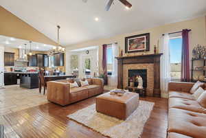 Living room featuring lofted ceiling, a fireplace, a wealth of natural light, and light hardwood / wood-style flooring