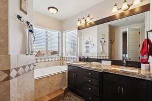 Bathroom featuring tiled tub and vanity