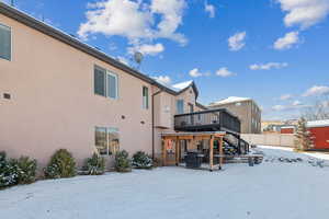 Snow covered house featuring a wooden deck