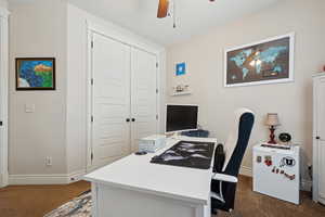 Office space featuring ceiling fan and dark carpet