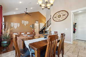 Dining area featuring ceiling fan with notable chandelier and vaulted ceiling