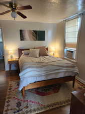 Bedroom featuring ceiling fan, cooling unit, dark hardwood / wood-style floors, and a textured ceiling