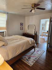 Bedroom featuring a textured ceiling, ceiling fan, cooling unit, and dark hardwood / wood-style floors