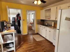 Kitchen featuring dark hardwood / wood-style flooring, sink, white fridge, and white cabinetry