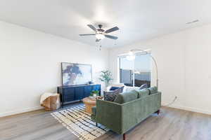 Living room with ceiling fan and light hardwood / wood-style floors