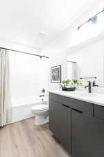 Full bathroom with toilet, vanity, shower / tub combo, and hardwood / wood-style floors