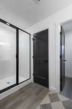 Bathroom featuring wood-type flooring and a shower with door