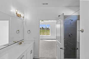 Bathroom with vanity, visible vents, and tiled shower