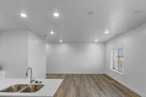 Kitchen with sink, white cabinetry, and hardwood / wood-style flooring