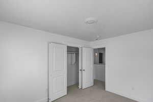 Bedroom 2 with light colored carpet and a closet