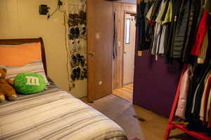 Carpeted bedroom featuring wood walls