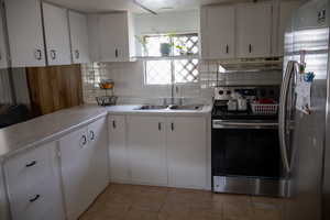 Kitchen with sink, light tile patterned floors, stainless steel appliances, white cabinets, and ventilation hood