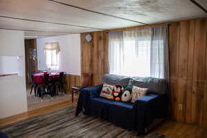 Living room with a wealth of natural light, wooden walls, and hardwood / wood-style floors