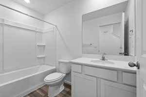 Full bathroom with toilet,  shower combination, hardwood / wood-style flooring, and vanity