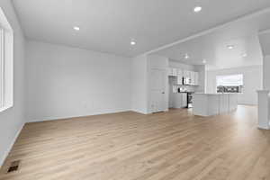 Unfurnished living room featuring sink and light wood-type flooring