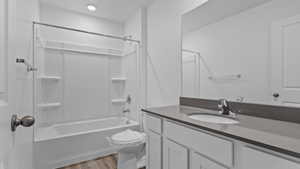 Full bathroom featuring hardwood / wood-style flooring, toilet, vanity, and shower / washtub combination