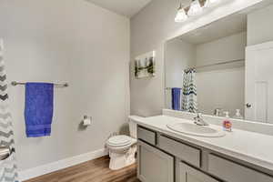 Bathroom featuring hardwood / wood-style floors, toilet, vanity, and walk in shower