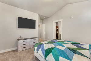 Carpeted bedroom with a spacious closet, a closet, and lofted ceiling