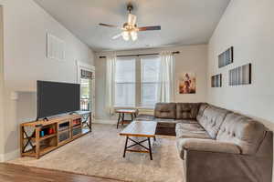 Living room featuring ceiling fan, lofted ceiling, and hardwood / wood-style flooring