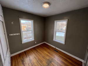 Unfurnished room featuring plenty of natural light, a textured ceiling, and hardwood / wood-style floors