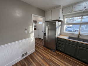 Kitchen featuring dark wood-type flooring, sink, white cabinetry, and stainless steel fridge with ice dispenser